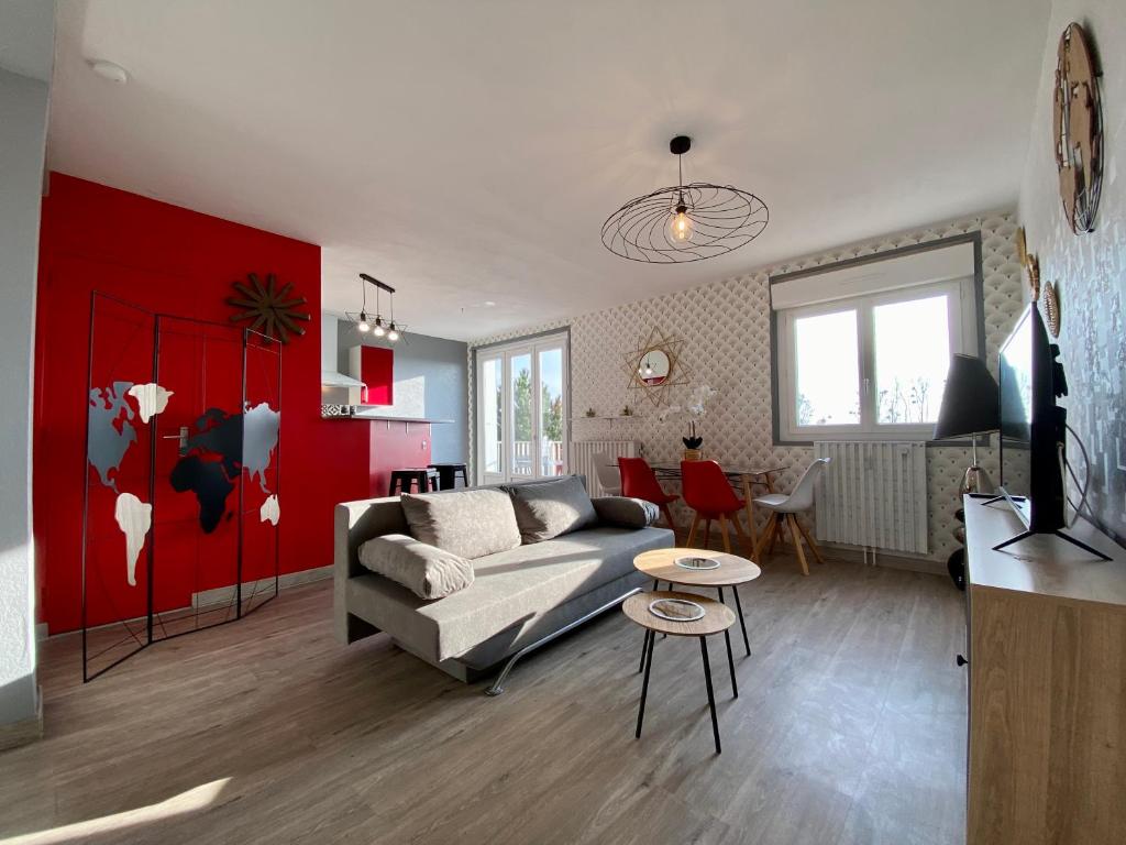 een woonkamer met een bank en een rode muur bij PANORAMA Balcony in Pontorson