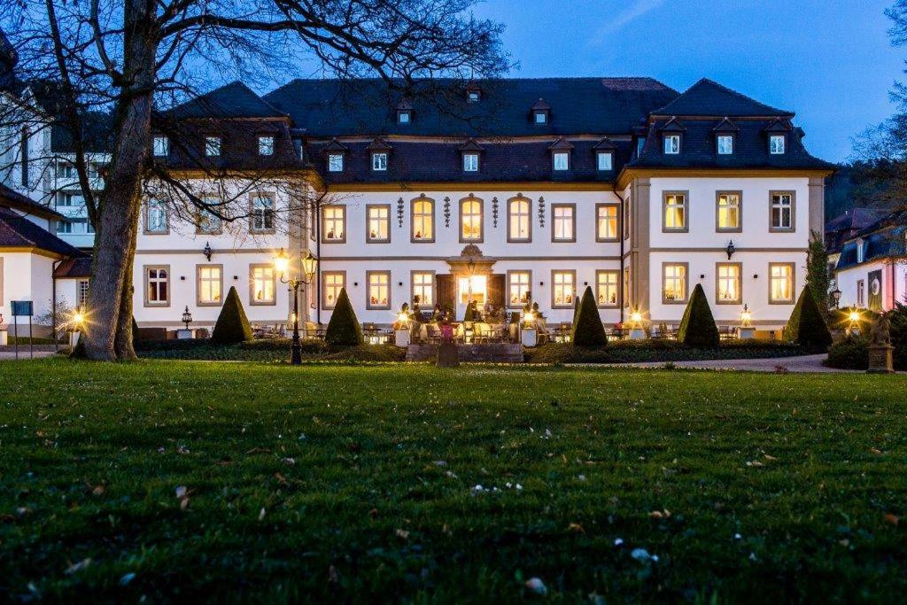 Une grande maison blanche avec des lumières dans la cour dans l'établissement Schlosshotel Bad Neustadt, à Bad Neustadt an der Saale