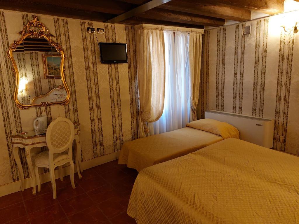 a bedroom with two beds and a desk and a mirror at Residenza Hotel San Maurizio in Venice