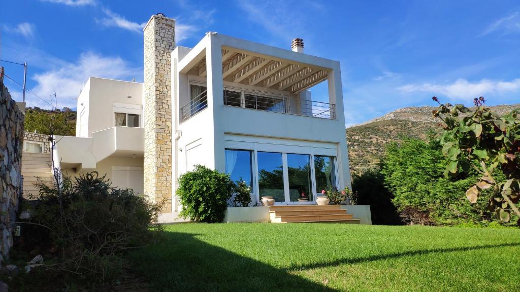 a white house with a green lawn at Villa with Aegean views in Akhladherí