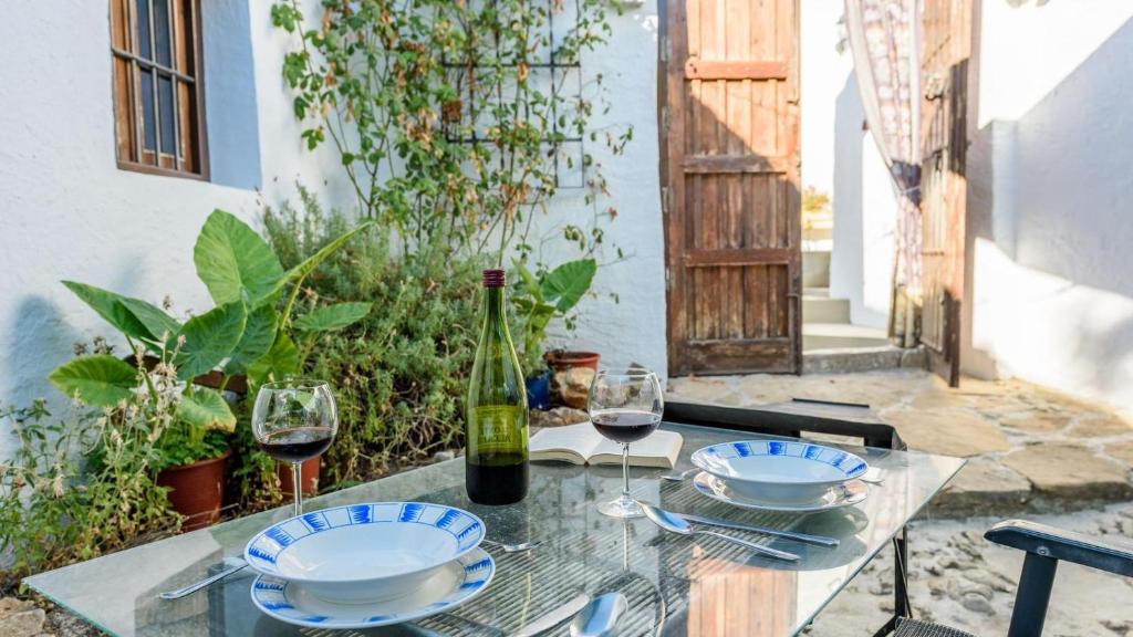 Molino Los Justos - Cocineta Algarinejo by Ruralidays في Algarinejo: طاولة مع طبقين وكؤوس من النبيذ