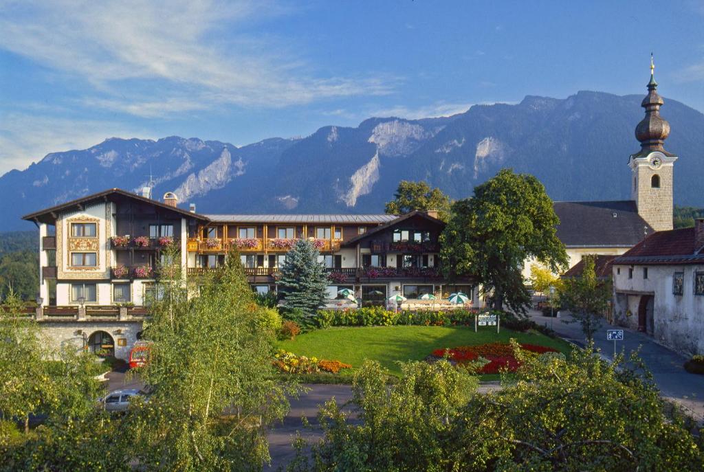 a building with a clock tower with mountains in the background at Schlossberghof Marzoll in Bad Reichenhall