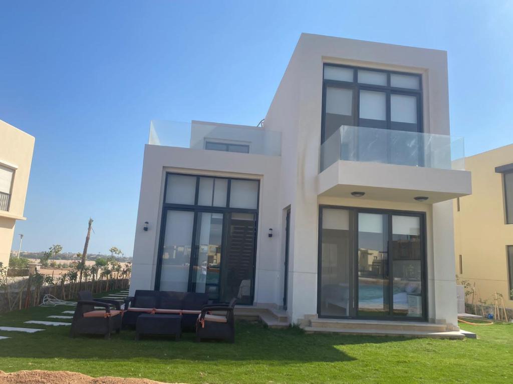 ein weißes Haus mit schwarzen Fenstern und grünem Gras in der Unterkunft Tawila, 4 Bedroom Villa, Brand new, directly on a lagoon in Hurghada