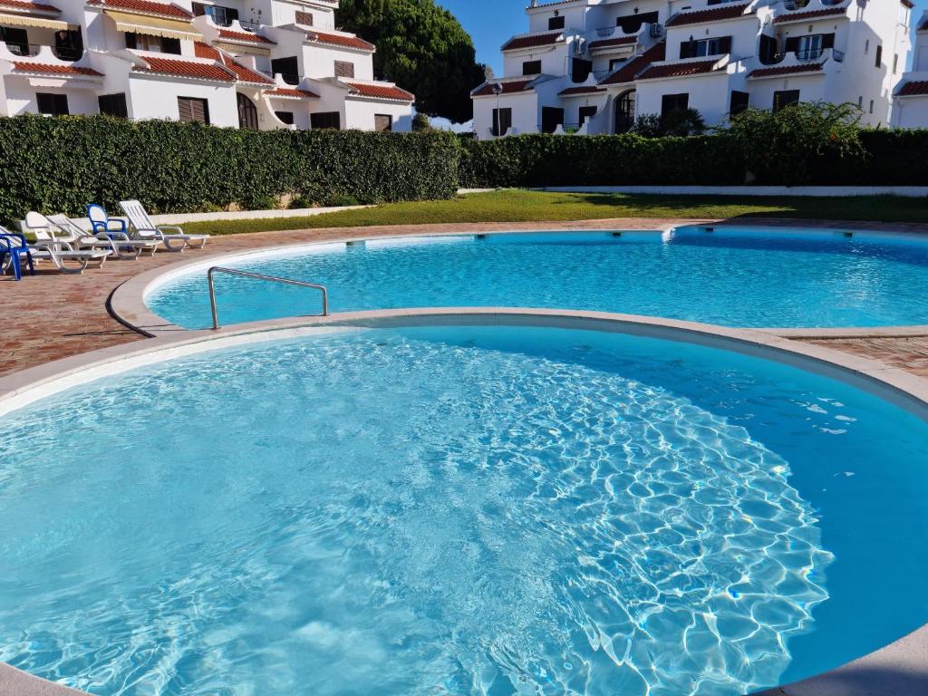 una grande piscina con acqua blu di fronte ad alcuni edifici di CASA DOCE Quinta Dos Arcos ad Alvor