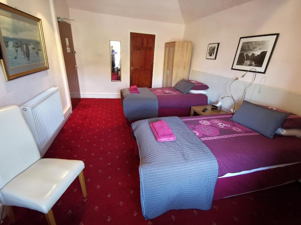 a hotel room with two beds and a chair at St Ronan's Hotel in Innerleithen