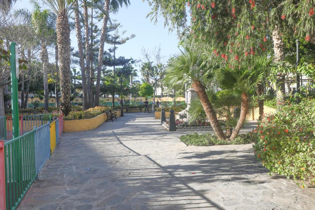 una pasarela en un parque con palmeras y una valla en Apartamento del Sol en Fuengirola