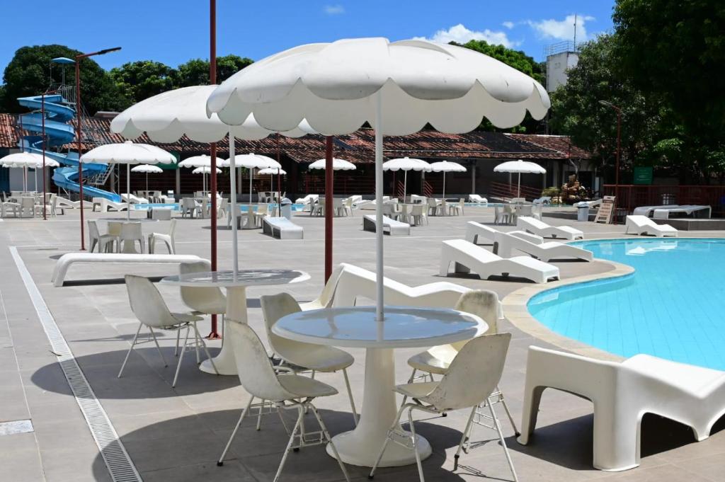 a patio with tables and chairs next to a pool at Hotel Sesi Aruana in Aruanã