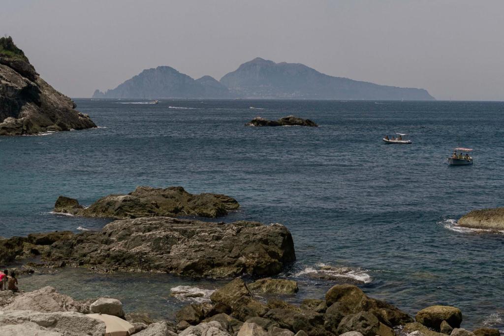 a body of water with rocks and boats in it at Maya Beach Resort in Massa Lubrense