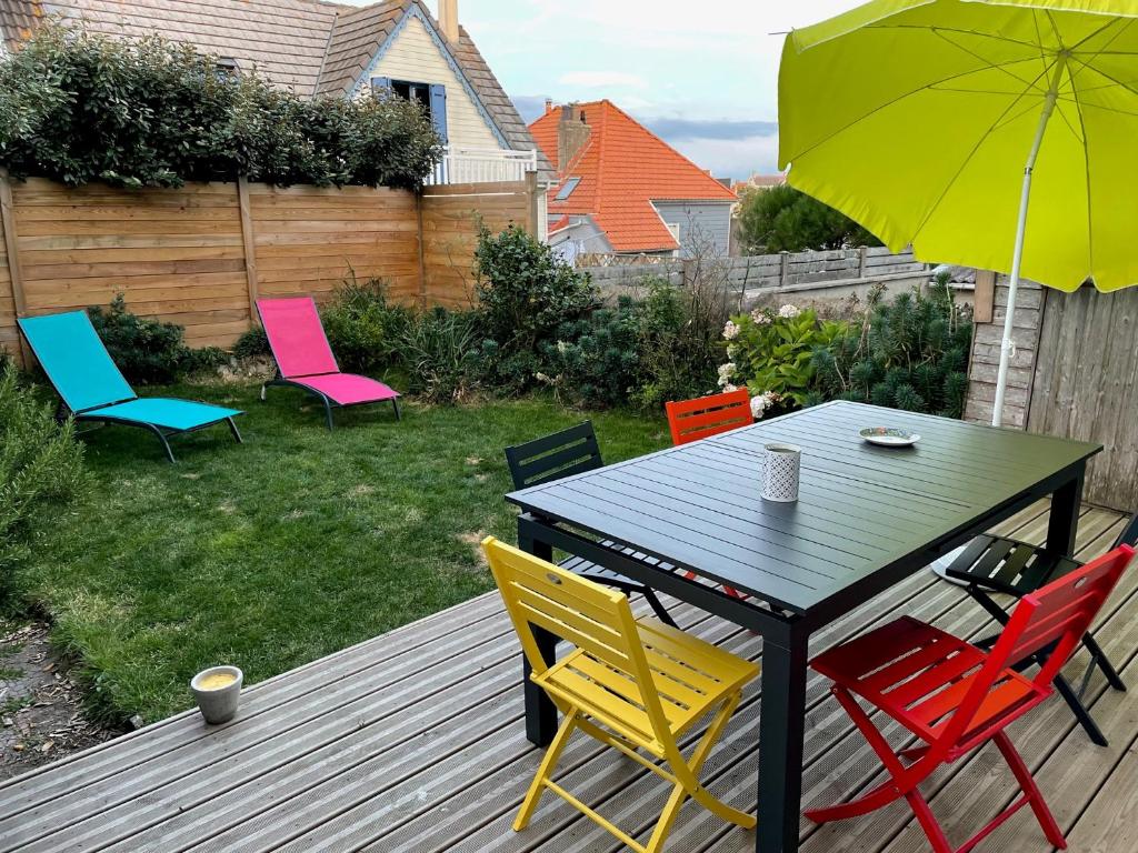 a table with colorful chairs and an umbrella on a deck at Du gite dans les Toiles in Wimereux