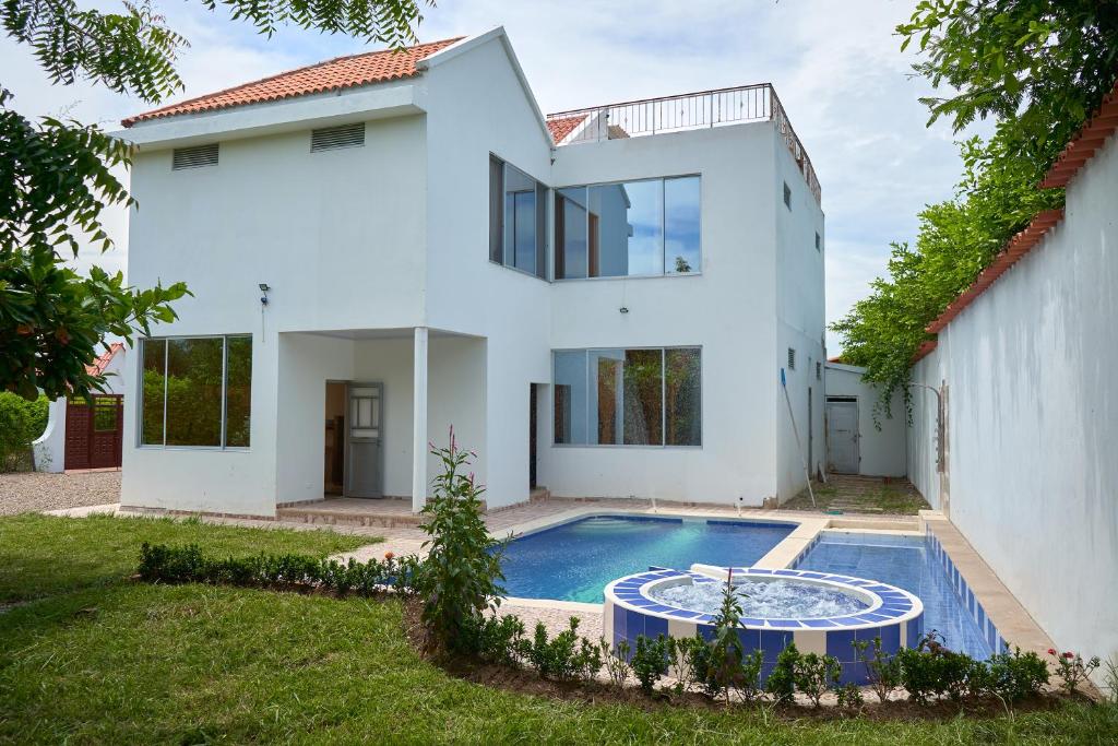 吉拉爾的住宿－Casa vacacional Girardot 5 habit，一座白色的房子,前面设有一个游泳池
