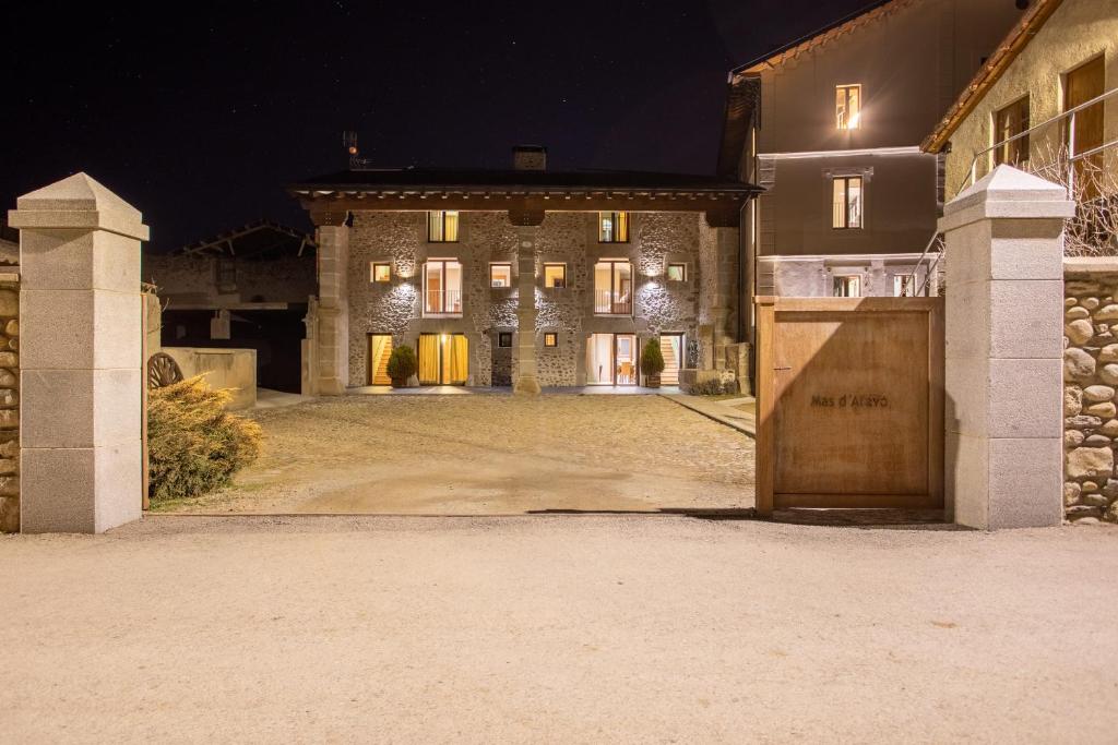 un gran edificio de piedra con garaje por la noche en Mas d'Aravó, en Bolvir