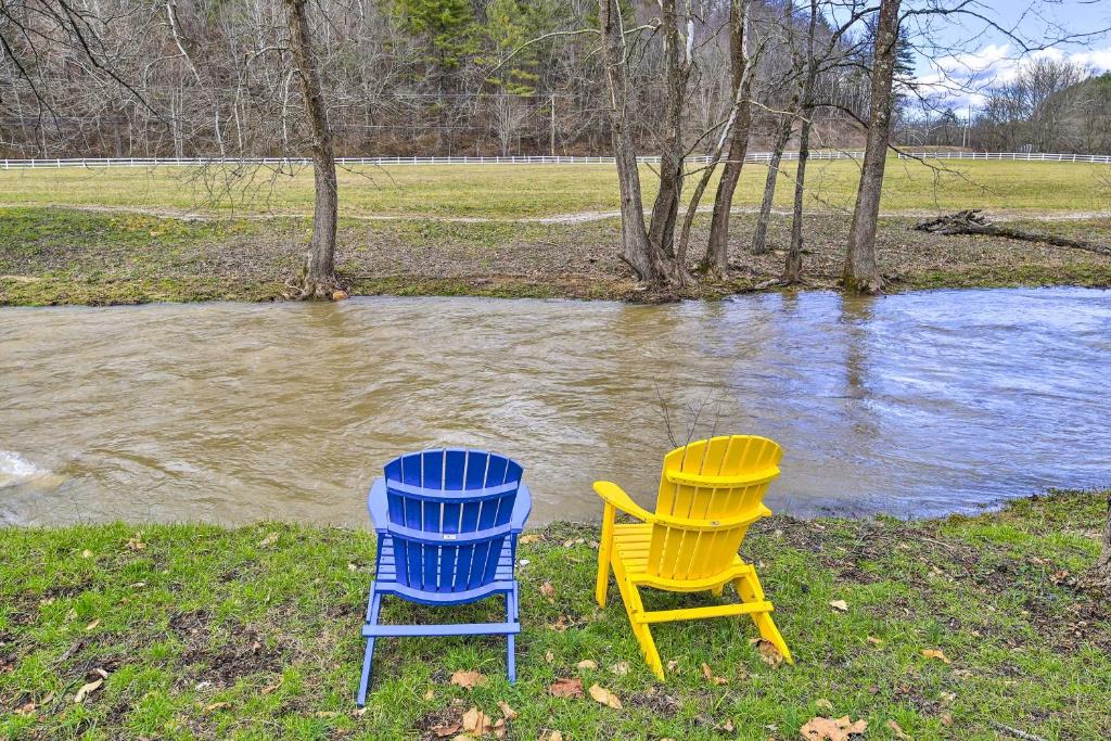 deux chaises assises dans l'herbe près d'une masse d'eau dans l'établissement Peaceful Cabin with Fire Pit on Cross Creek Ranch!, à Mountain City