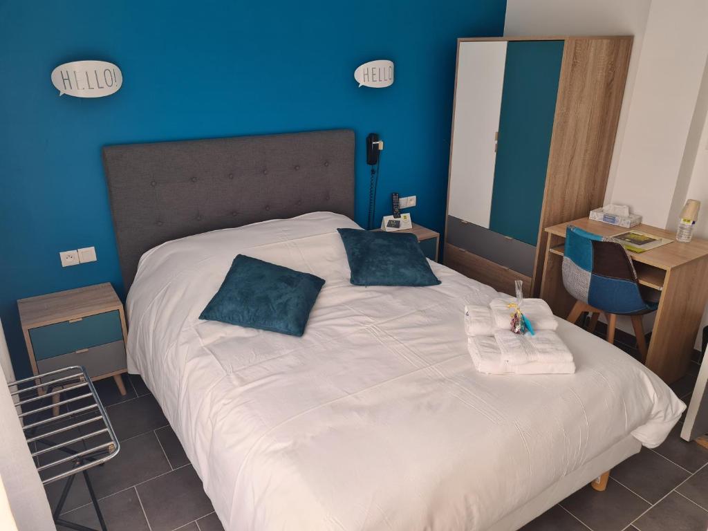 um quarto com uma grande cama branca com paredes azuis em Logis Le Franco Belge em Monthermé
