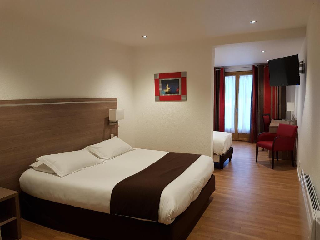 FerrièresにあるLogis Hotel Restaurant de l'Abbayeの大きなベッドと椅子が備わるホテルルームです。