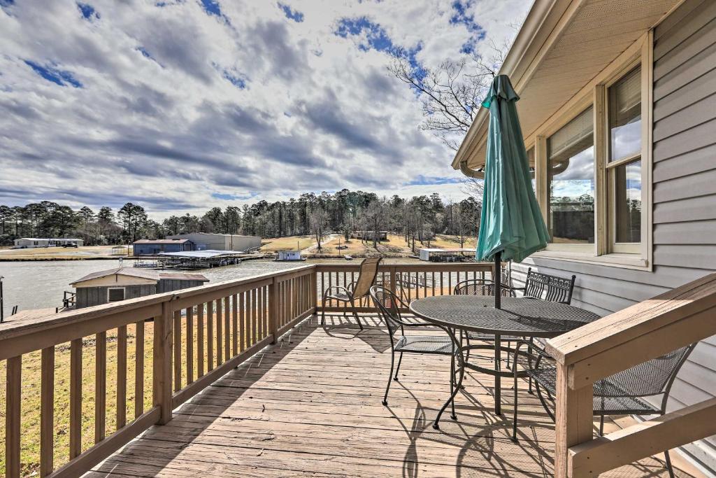 een terras met een tafel en stoelen en een parasol bij Lake Sinclair Cottage with Deck and Boat Dock! in Milledgeville