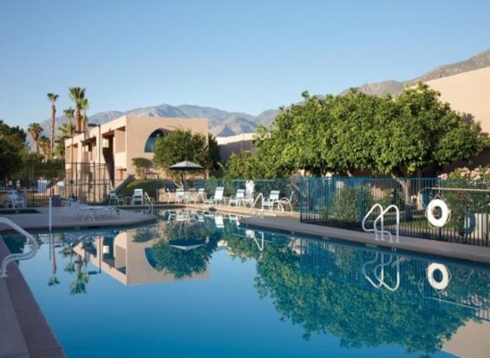 una piscina en un complejo con sillas y árboles en GetAways at Vista Mirage Resort en Palm Springs