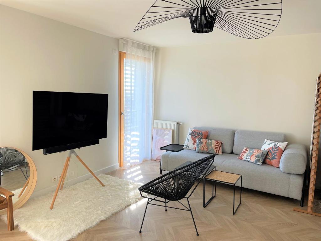 a living room with a couch and a flat screen tv at APPART 2P AVEC PARKING ET BALCON - gare val d'europe 5mn - disney 10mn in Montévrain
