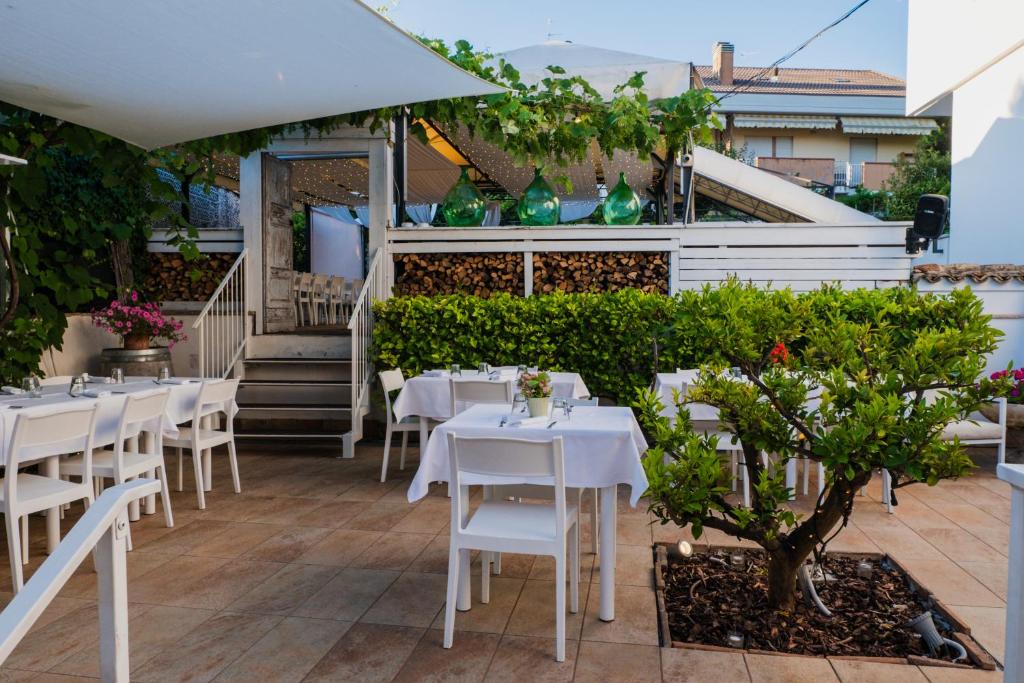 restauracja z białymi stołami i krzesłami na patio w obiekcie La Taverna Antica Rooms w mieście Pescara