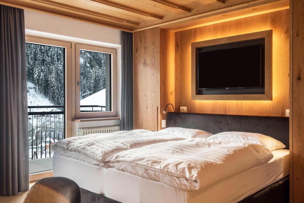 1 dormitorio con 1 cama y TV en la pared en La Grambla App Saslonch 1 en Santa Cristina in Val Gardena