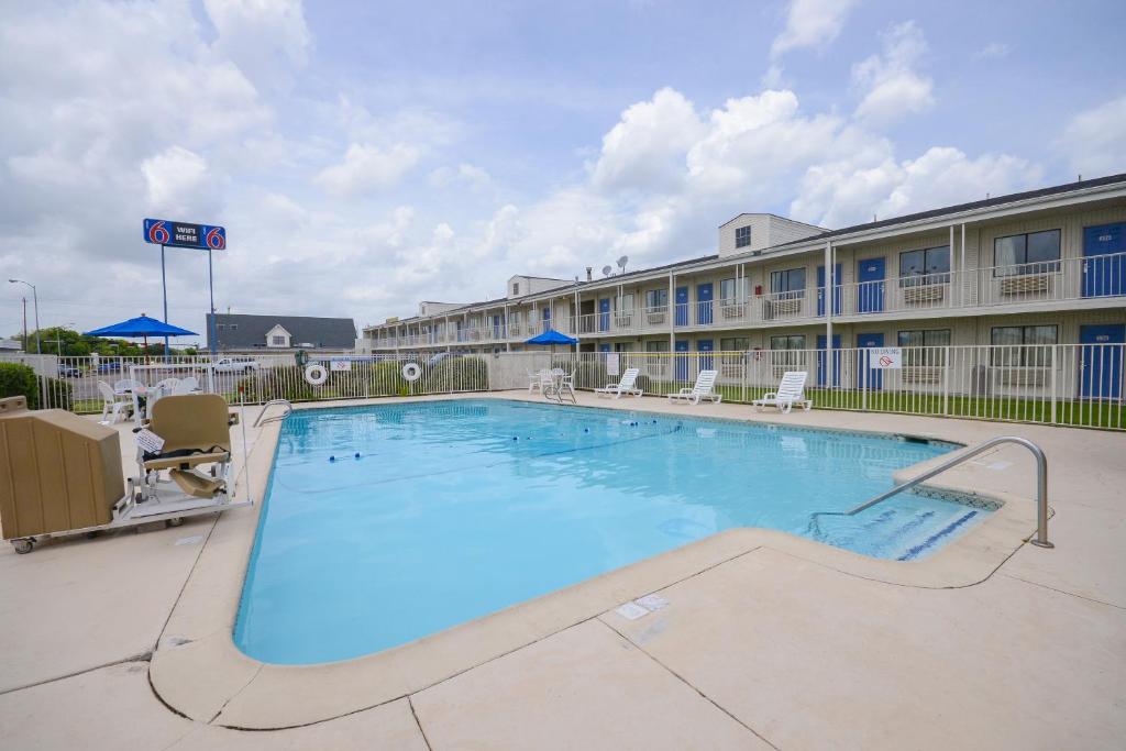 a large pool with chairs and a hotel at Motel 6-Webster, TX - Houston - Nasa Lake in Webster