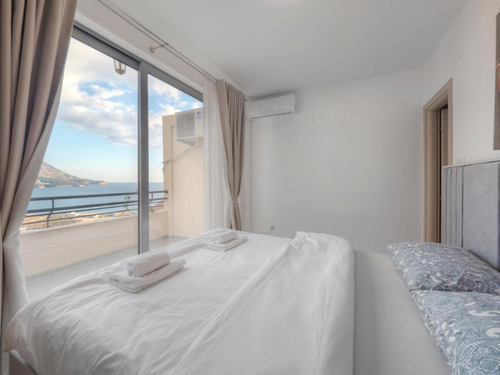 a bedroom with a bed and a large window at Sea view Two bedroom Family Apartment with pool - Sunset Ivanovići in Becici