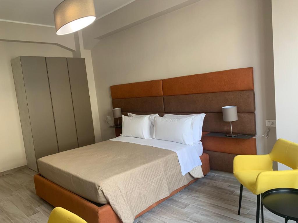 a bedroom with a large bed and a yellow chair at Tripepi suites in Reggio Calabria