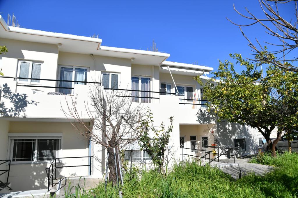 a white building with black balconies and trees at Iskas apartments in Ialyssos