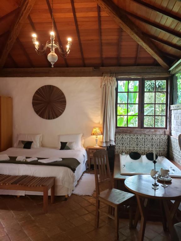 a bedroom with a bed and a table and chairs at A Arte de Bem Viver in Tiradentes