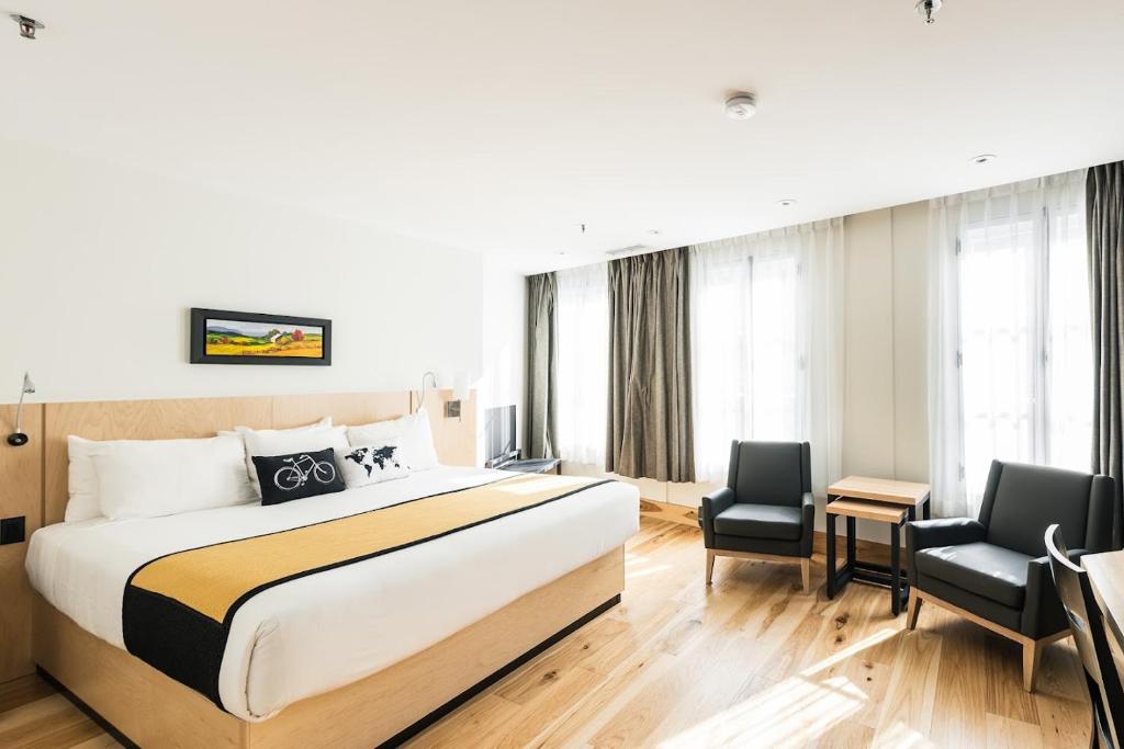 a hotel room with a large bed and two chairs at Hotel du Vieux Quebec in Quebec City