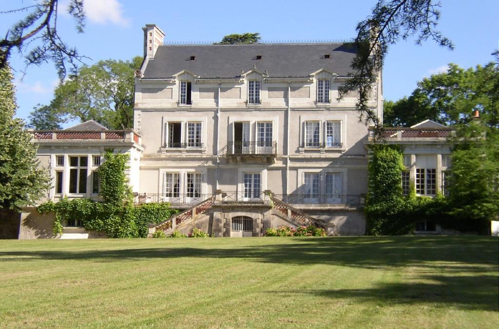 una grande casa bianca con un ampio cortile di Appartement du Château du Grand Bouchet a Ballan-Miré