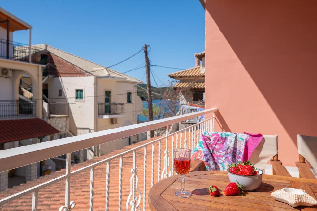 a table with a glass of wine and strawberries on a balcony at Τrilogy Studios in Syvota