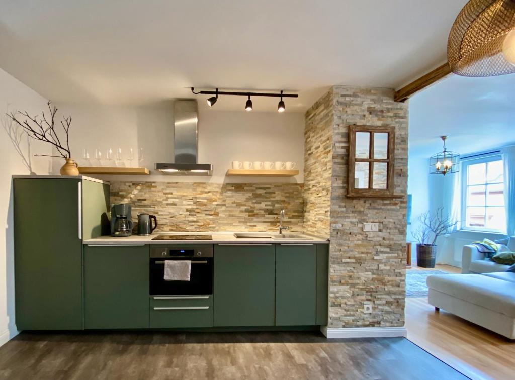 eine Küche mit grünen Schränken und einer Ziegelwand in der Unterkunft Grünberg House in Traben-Trarbach