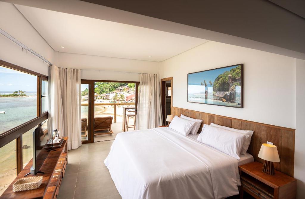 a bedroom with a bed and a view of the ocean at One Beach Boutique Hotel in Morro de São Paulo