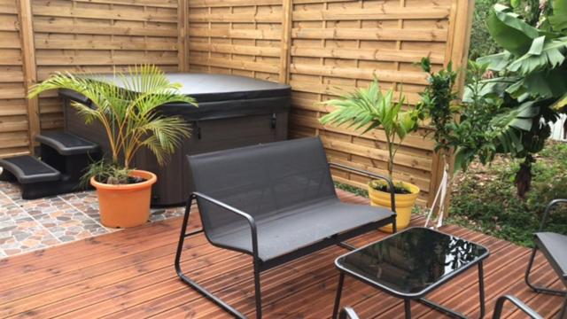 a patio with a hot tub and a chair and plants at Le Saintois in Terre-de-Bas