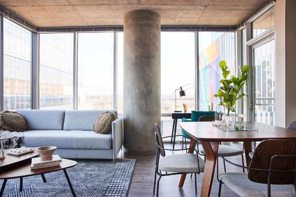 a living room with a couch and tables and windows at Placemakr Premier SoBro in Nashville