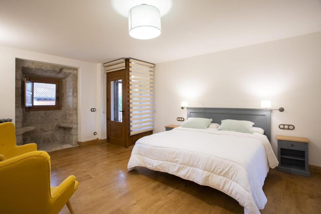 a bedroom with a large white bed and a yellow chair at Casa Rural Llanes Asturias in Llanes