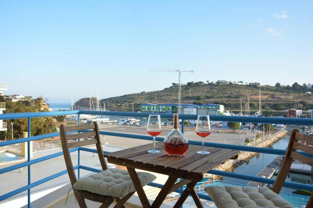 - deux verres de vin assis sur une table en bois sur un balcon dans l'établissement Wonderful Apartment Albufeira Marina 4B 2B, à Albufeira