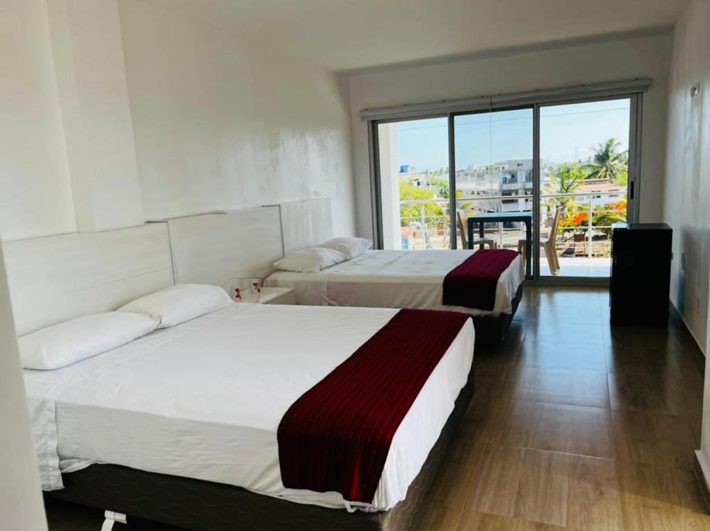 two beds in a room with a large window at Sumaq House offer a new suite in Puerto Ayora