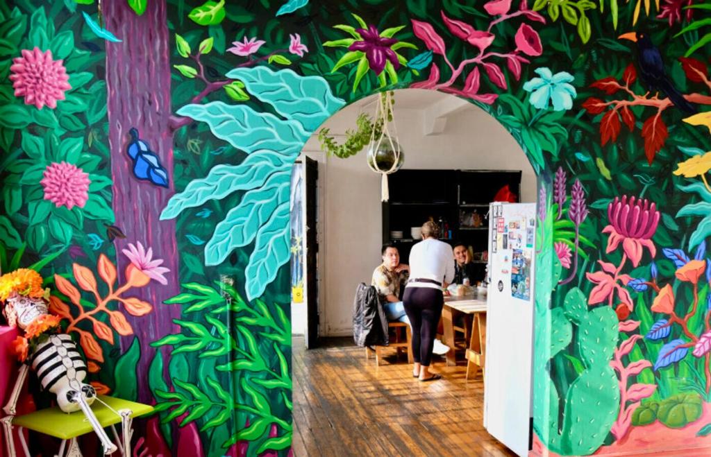 a room with a colorful wall with people sitting at a table at Massiosare El Hostal in Mexico City