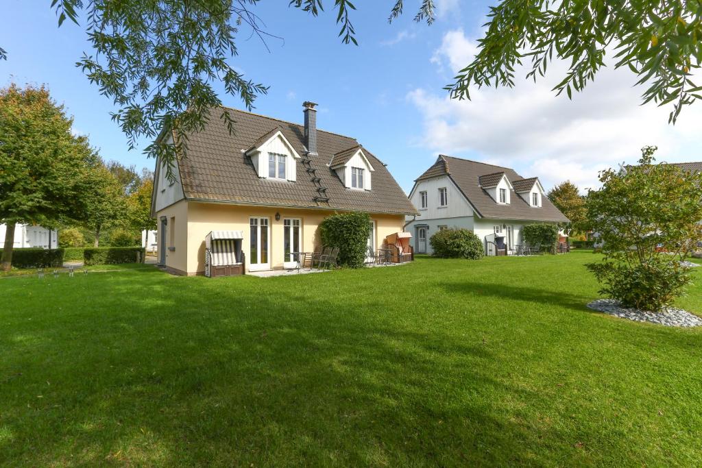 uma casa com um grande quintal com relva verde em Ostseeferienpark Seepferdchen direkt an der Ostsee - perfekt für Familien em Ostseebad Nienhagen