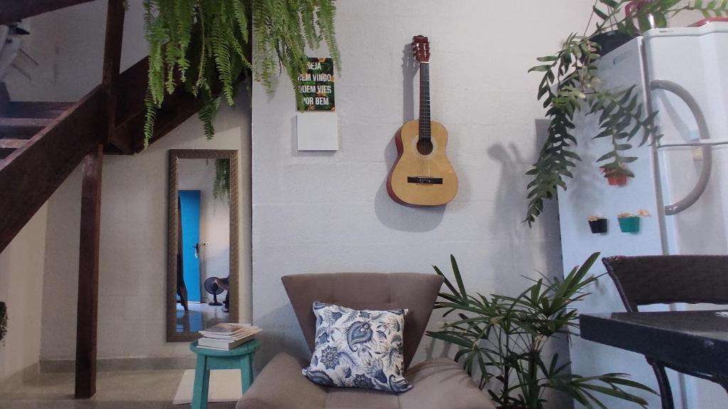 a room with a chair and a guitar on the wall at Loft Pousada Sorriso in Sorriso
