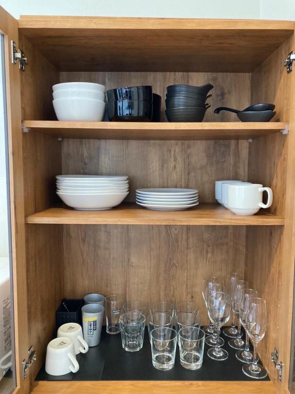 a wooden cabinet with dishes and glasses on it at KAI Ichinomiya in Ichinomiya