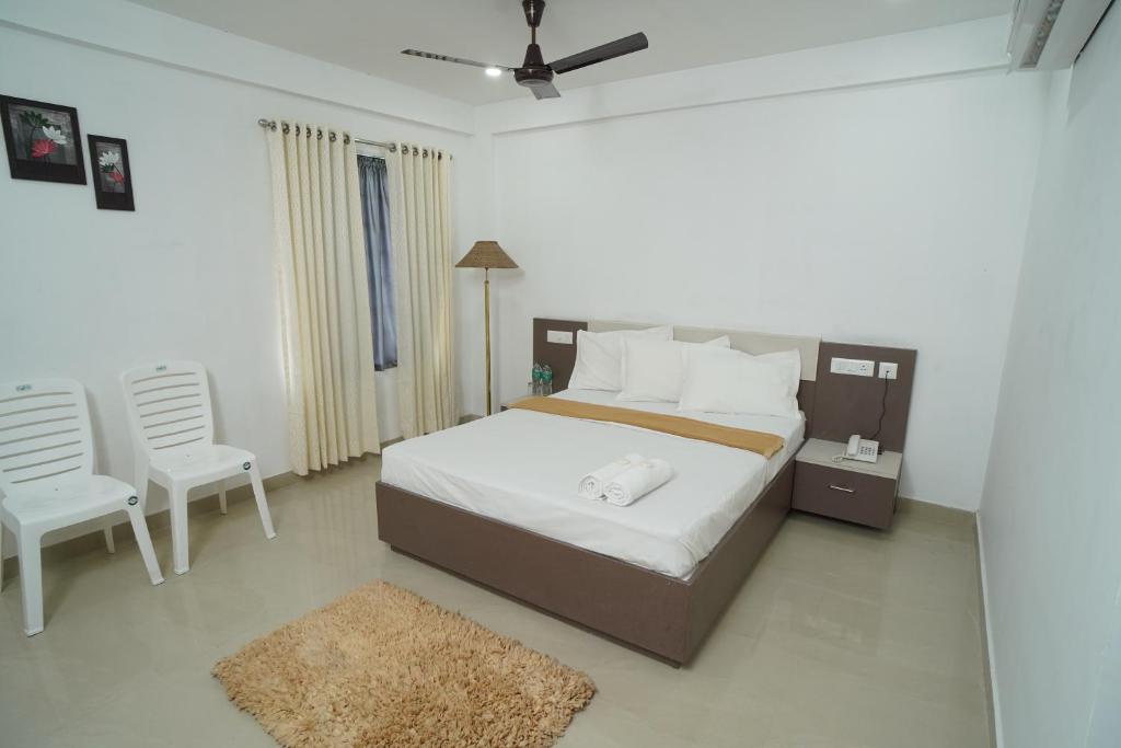 Un dormitorio con una cama grande y dos sillas. en SN ROOMS, en Perumpāvūr