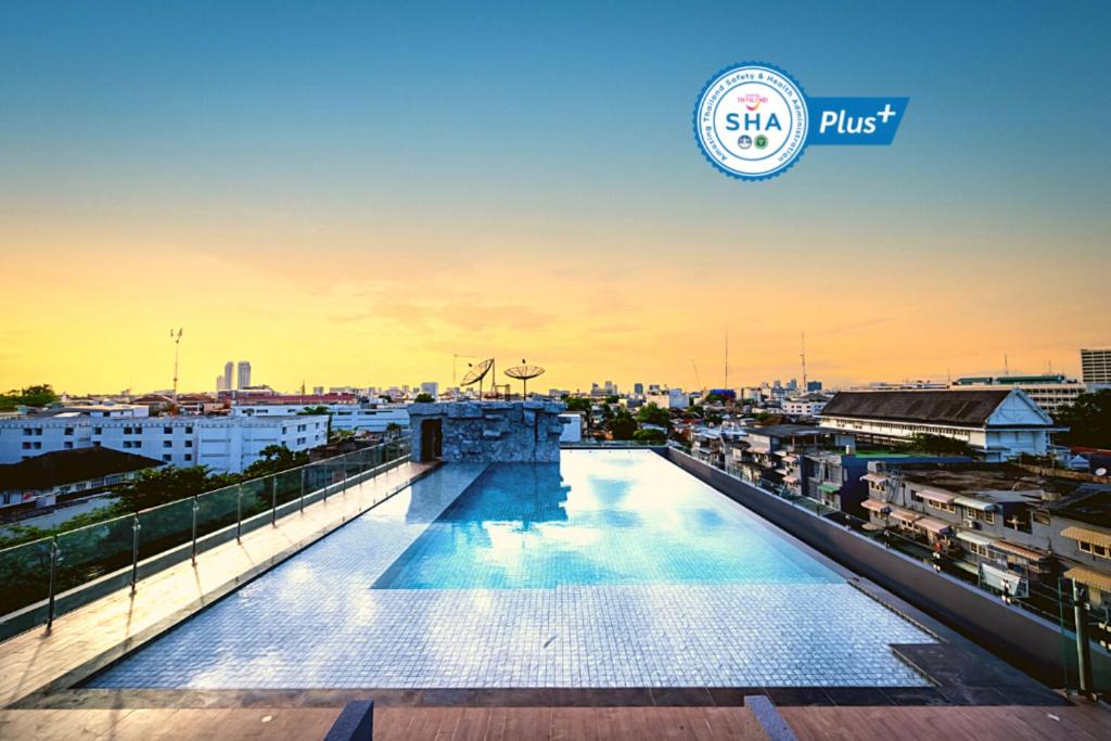 A rooftop infinity-style pool overlooking Bangkok at sunset.