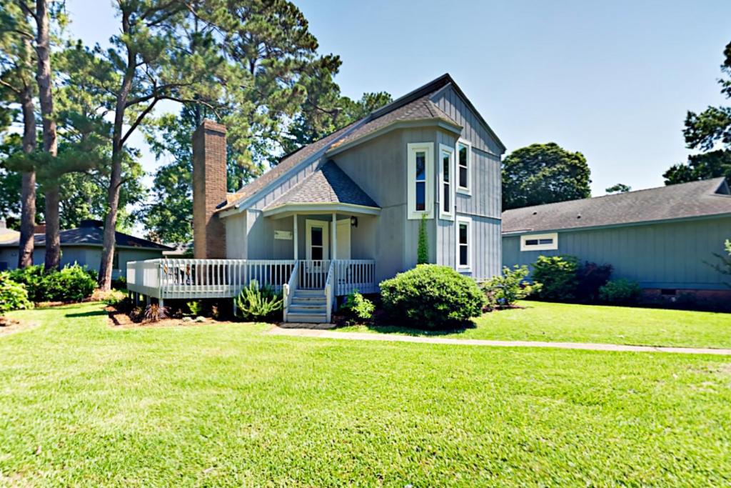 a blue house with a grass yard at Cozy Beach Retreat in Myrtle Beach