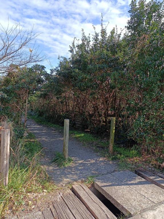 a dirt trail with a wooden fence and trees at KAI Ichinomiya in Ichinomiya