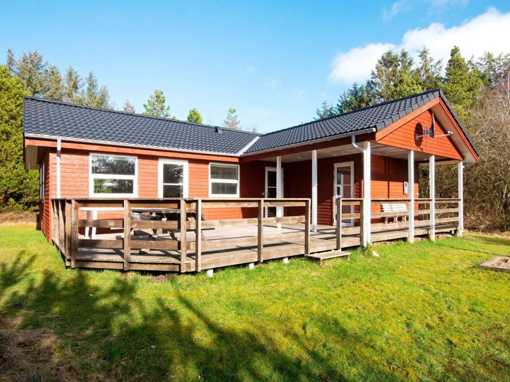 a log cabin with a large deck in the grass at 6 person holiday home in R m in Bolilmark