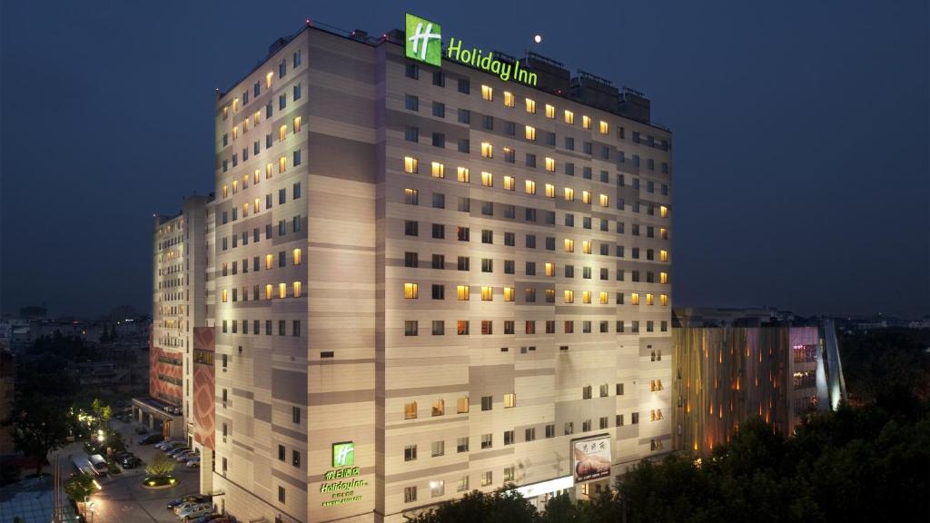 Un alto edificio bianco con un cartello verde di Holiday Inn Nanjing Aqua City, an IHG Hotel a Nanjing