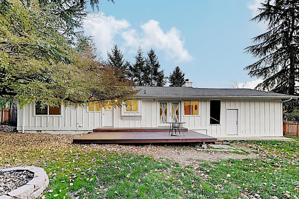 ein weißes Haus mit einer Terrasse davor in der Unterkunft Farmhouse-Chic Retreat in Lynwood Center