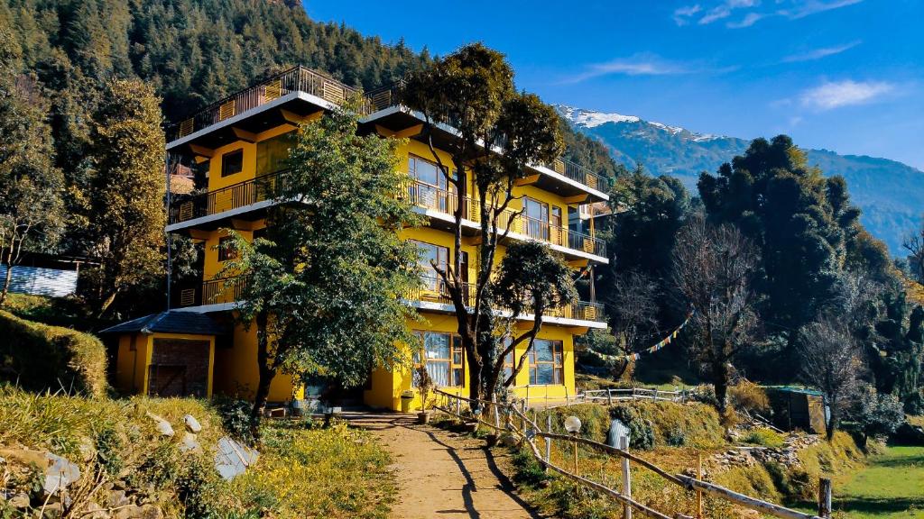 a yellow building on the side of a mountain at The Hosteller Mcleodganj, Upper Bhagsu in McLeod Ganj